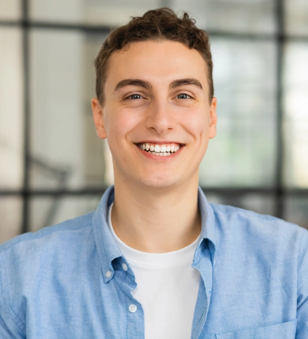 Portrait of a smiling young man with a healthy bright smile wearing a blue button-down shirt