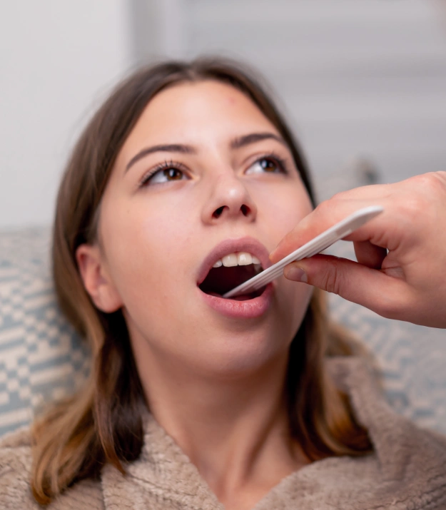Dentist using a tongue depressor to examine a patient's mouth during an oral cancer screening