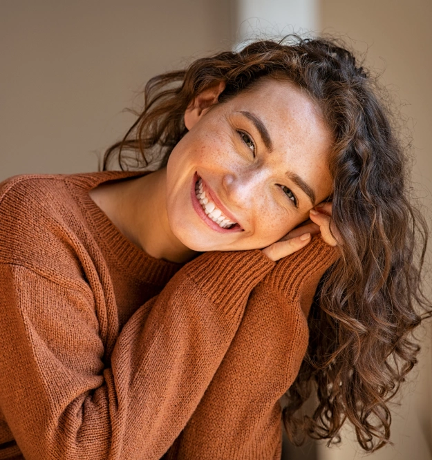 Woman in Brown Sweater Smiling after getting Dental Treatment